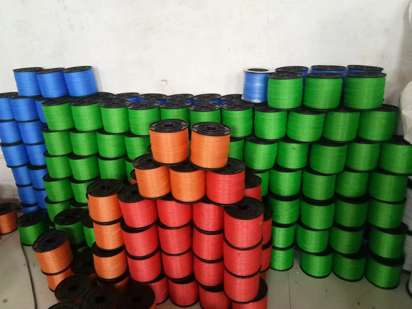 Electric-fence polyrope reels in blue, green, orange and red stacked in a warehouse