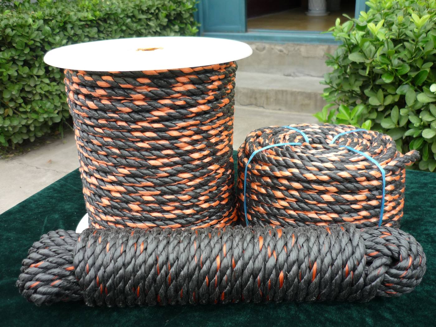Mixed orange and black 3-strand twisted utility rope wound on a plastic spool